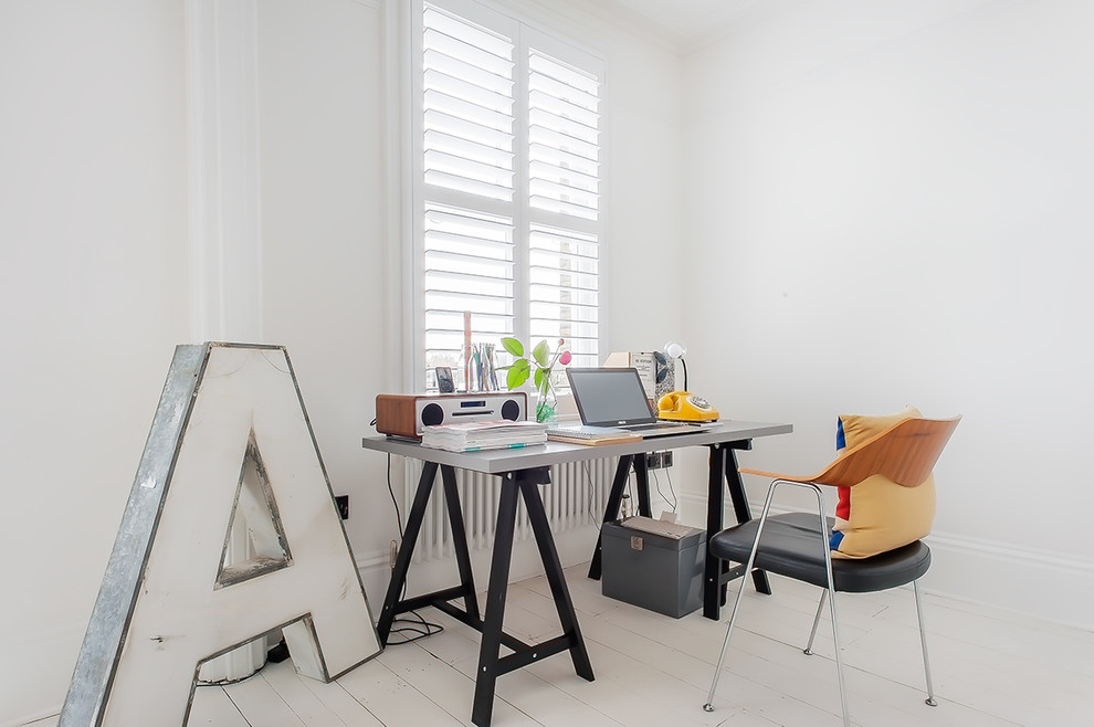 This is an example of a contemporary study in London with white walls, painted wood flooring, a freestanding desk and white floors.