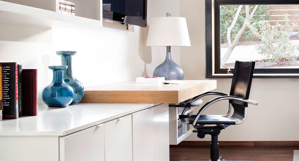 Immagine di un piccolo ufficio moderno con pareti bianche, parquet scuro e scrivania incassata