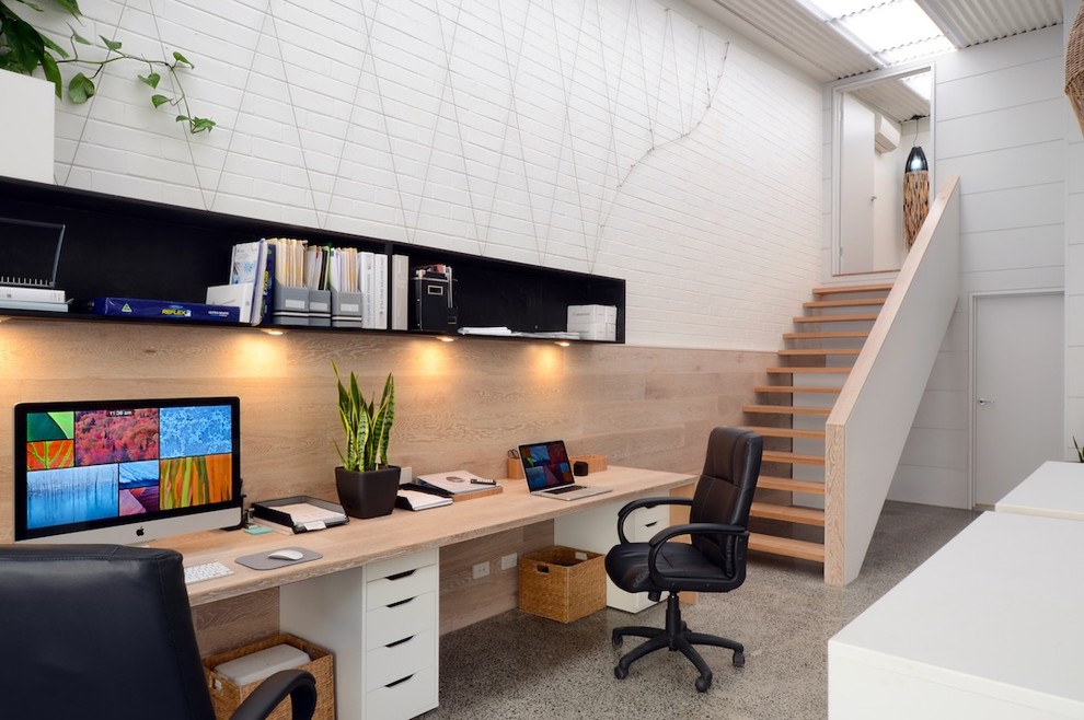 Modelo de despacho minimalista de tamaño medio con paredes blancas, suelo de cemento y escritorio empotrado