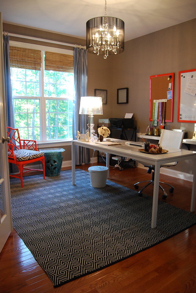 Example of a trendy freestanding desk dark wood floor home office design in Raleigh with brown walls