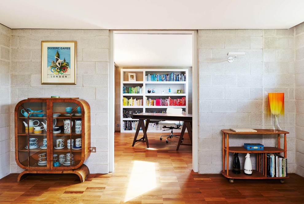 Idéer för mellanstora funkis hemmabibliotek, med grå väggar, mellanmörkt trägolv och ett fristående skrivbord