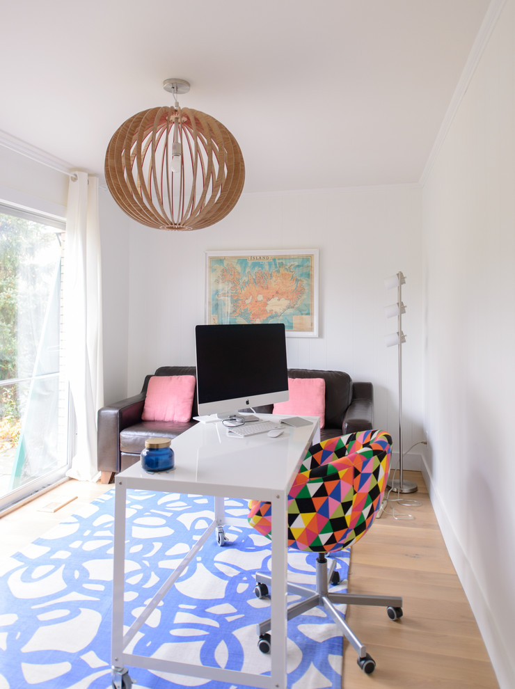 Modern inredning av ett mellanstort arbetsrum, med ett fristående skrivbord, vita väggar och ljust trägolv