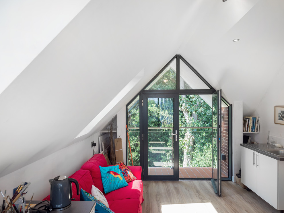 This is an example of a medium sized modern home studio in West Midlands with white walls, vinyl flooring, no fireplace, a built-in desk and brown floors.