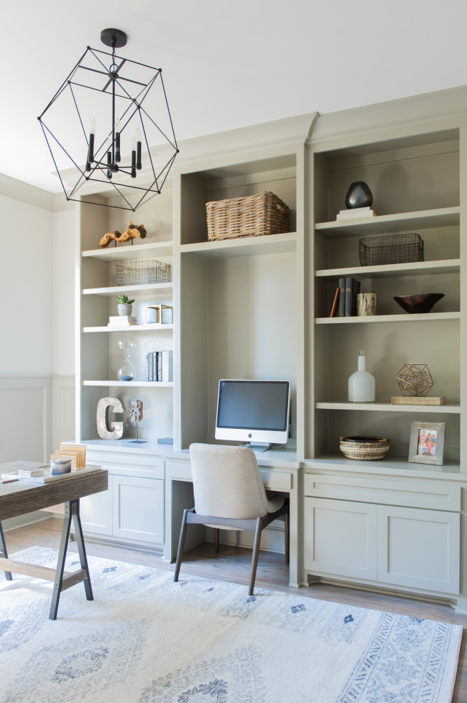 Inspiration for a transitional built-in desk medium tone wood floor, brown floor and wainscoting home office remodel in Nashville with white walls