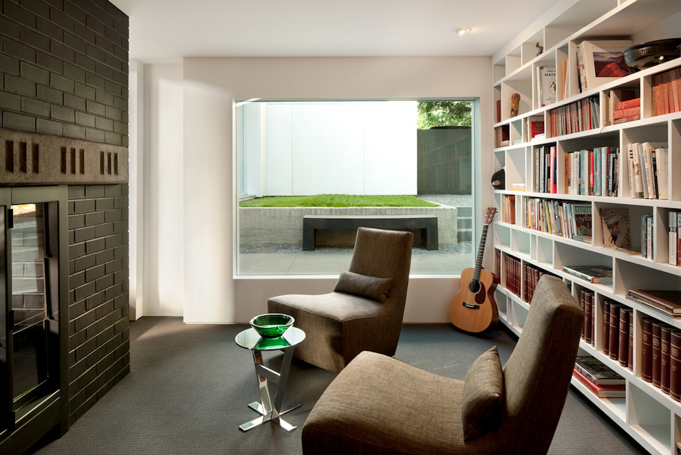 Inspiration för mellanstora moderna arbetsrum, med ett bibliotek, vita väggar, heltäckningsmatta, en dubbelsidig öppen spis, en spiselkrans i tegelsten och grått golv