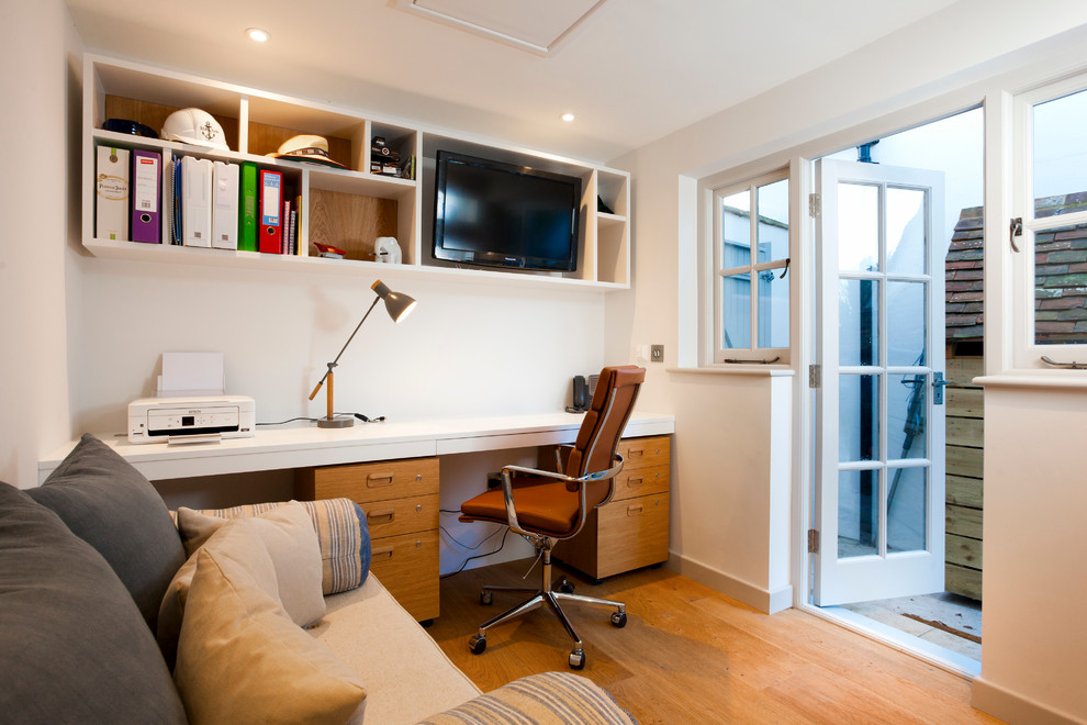 Cette photo montre un bureau nature de taille moyenne avec un mur blanc, un sol en bois brun, aucune cheminée et un bureau intégré.