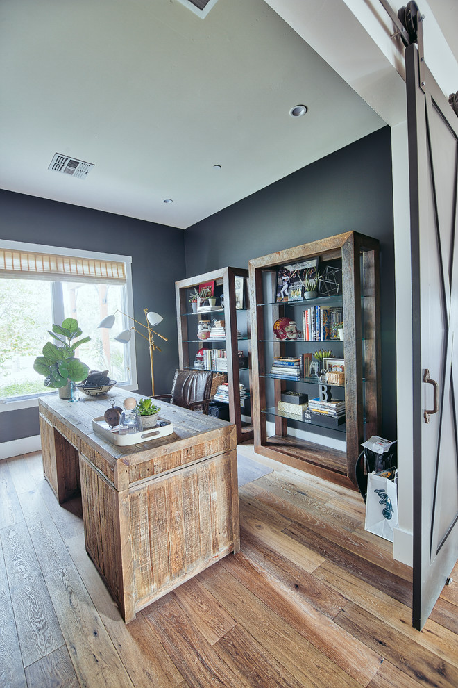 Foto de despacho minimalista grande sin chimenea con paredes grises, suelo de madera en tonos medios y escritorio independiente