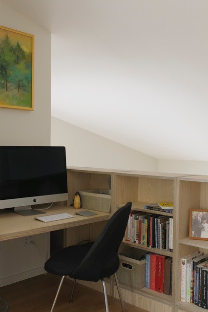 Aménagement d'un petit bureau moderne avec un mur blanc, parquet foncé et un bureau intégré.