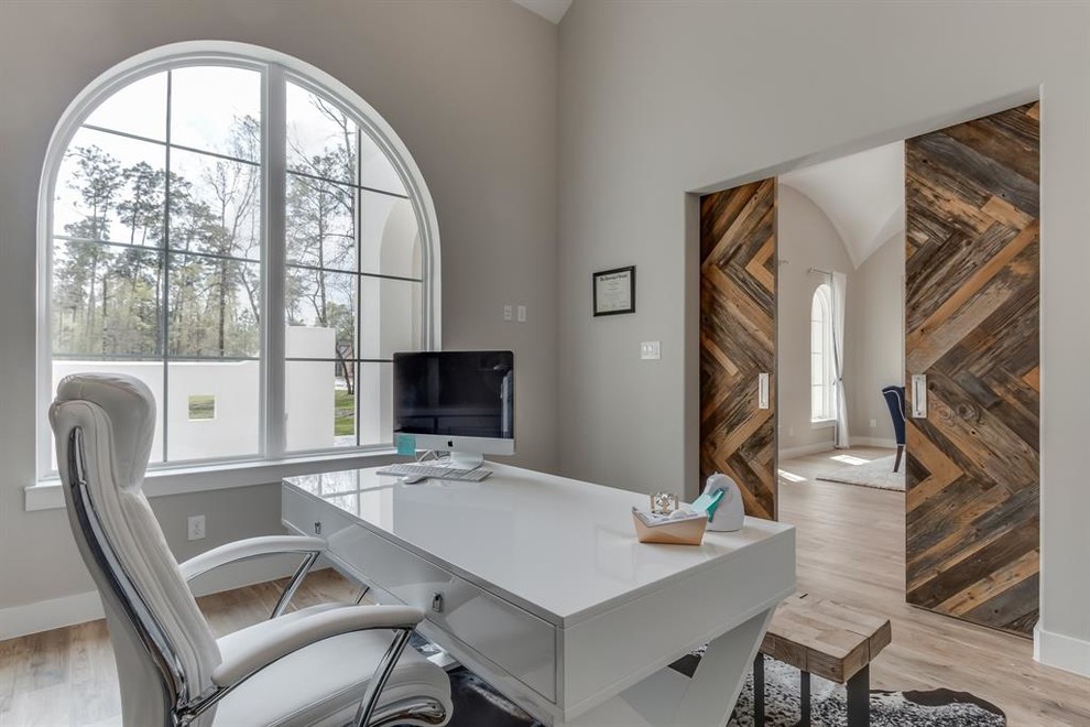 Ejemplo de despacho minimalista grande con paredes grises, suelo de madera clara, escritorio independiente y suelo beige