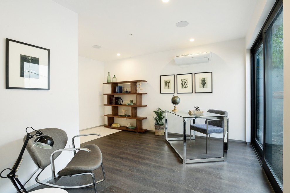 Modernes Arbeitszimmer ohne Kamin mit weißer Wandfarbe, dunklem Holzboden und freistehendem Schreibtisch in Los Angeles