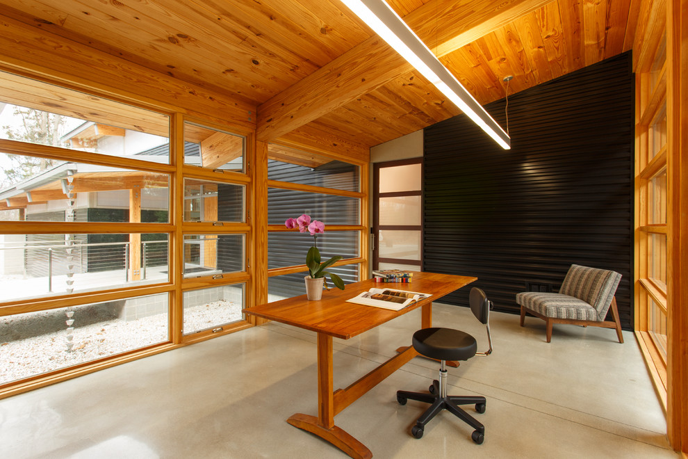 Ejemplo de despacho minimalista con suelo de cemento y escritorio independiente