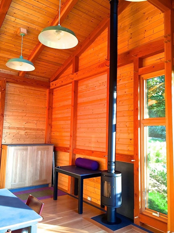 Foto de estudio moderno pequeño con suelo de madera en tonos medios y estufa de leña