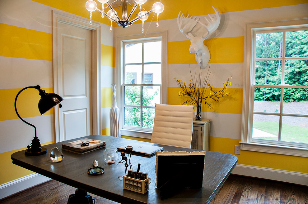 Esempio di uno studio minimal con pareti gialle, parquet scuro e scrivania autoportante