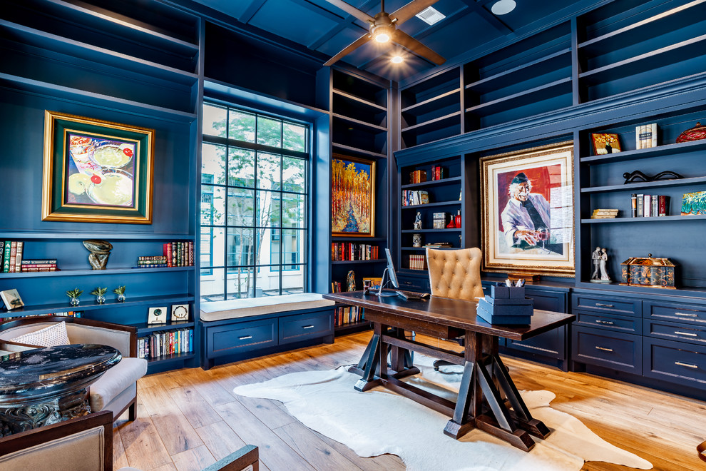 Großes Klassisches Arbeitszimmer mit Arbeitsplatz, blauer Wandfarbe, hellem Holzboden, freistehendem Schreibtisch und braunem Boden in Houston