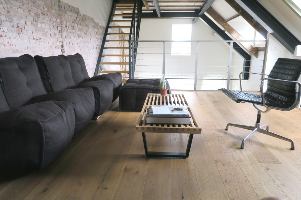 Imagen de estudio industrial grande sin chimenea con paredes blancas, suelo de madera clara, escritorio independiente y suelo marrón