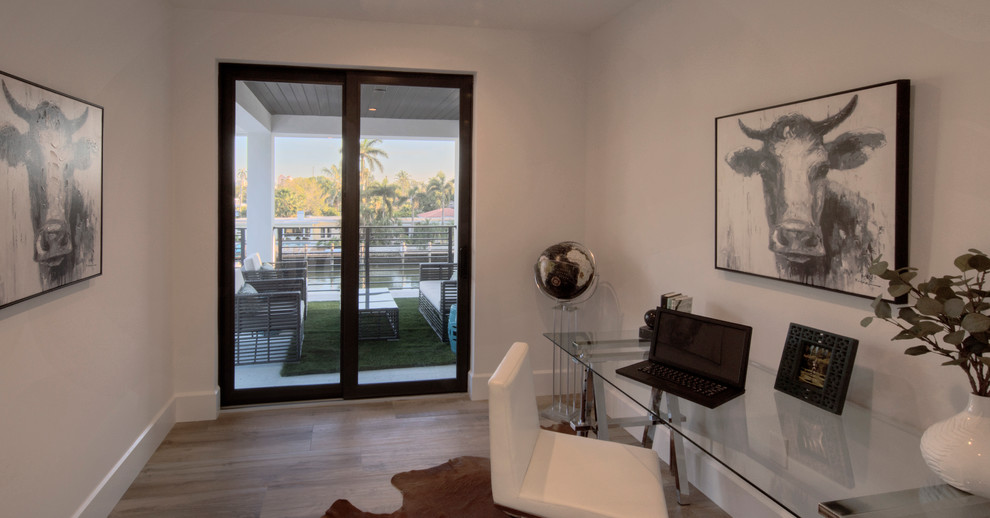 This is an example of a medium sized contemporary home studio in Miami with white walls, medium hardwood flooring, a freestanding desk and brown floors.