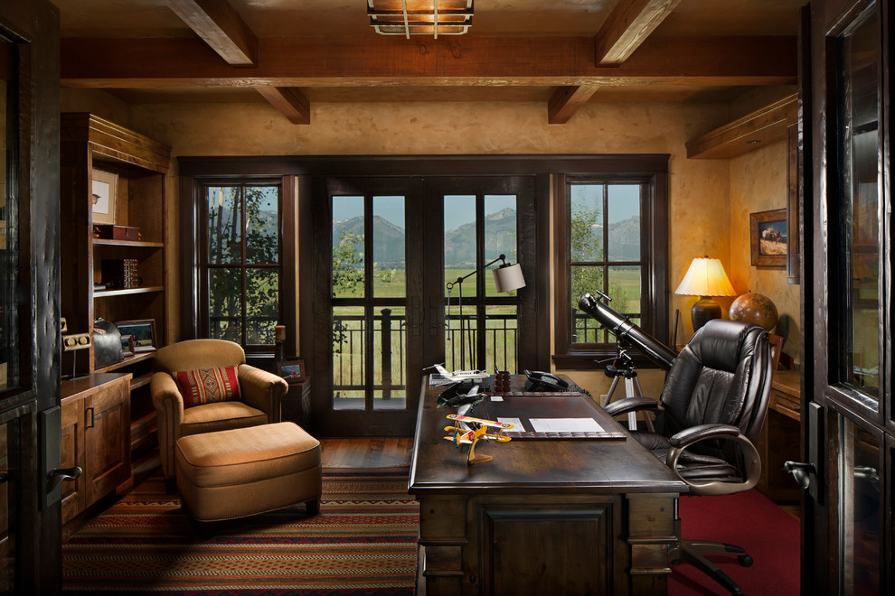 Ejemplo de despacho rural grande sin chimenea con paredes beige, suelo de madera oscura, escritorio independiente y suelo marrón