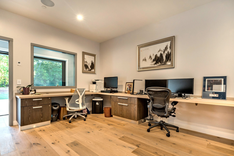Large trendy built-in desk light wood floor study room photo in San Francisco with white walls