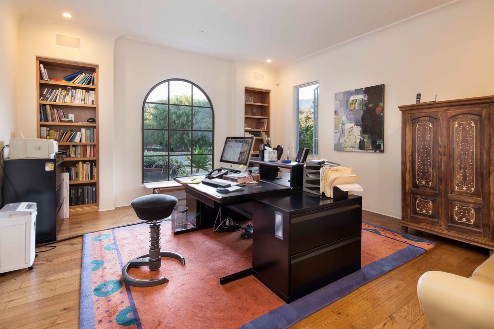 Example of a large tuscan freestanding desk medium tone wood floor study room design in Santa Barbara with white walls