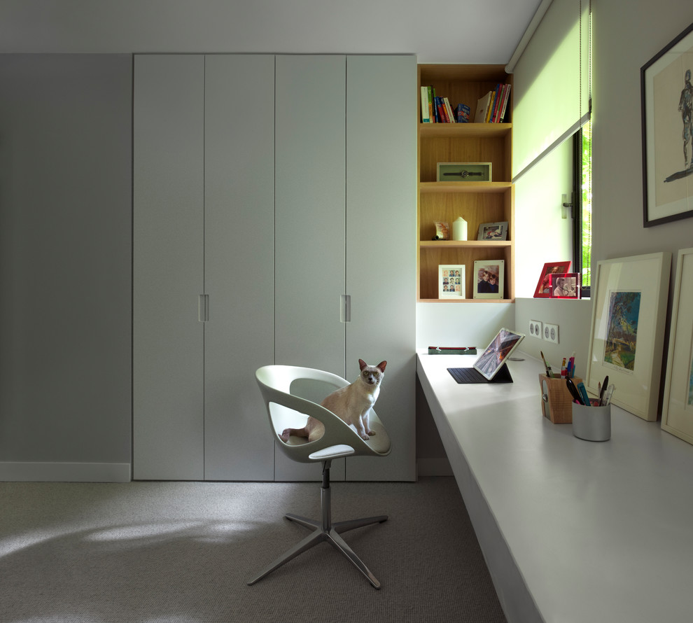 Home office - contemporary built-in desk carpeted and gray floor home office idea in London with gray walls