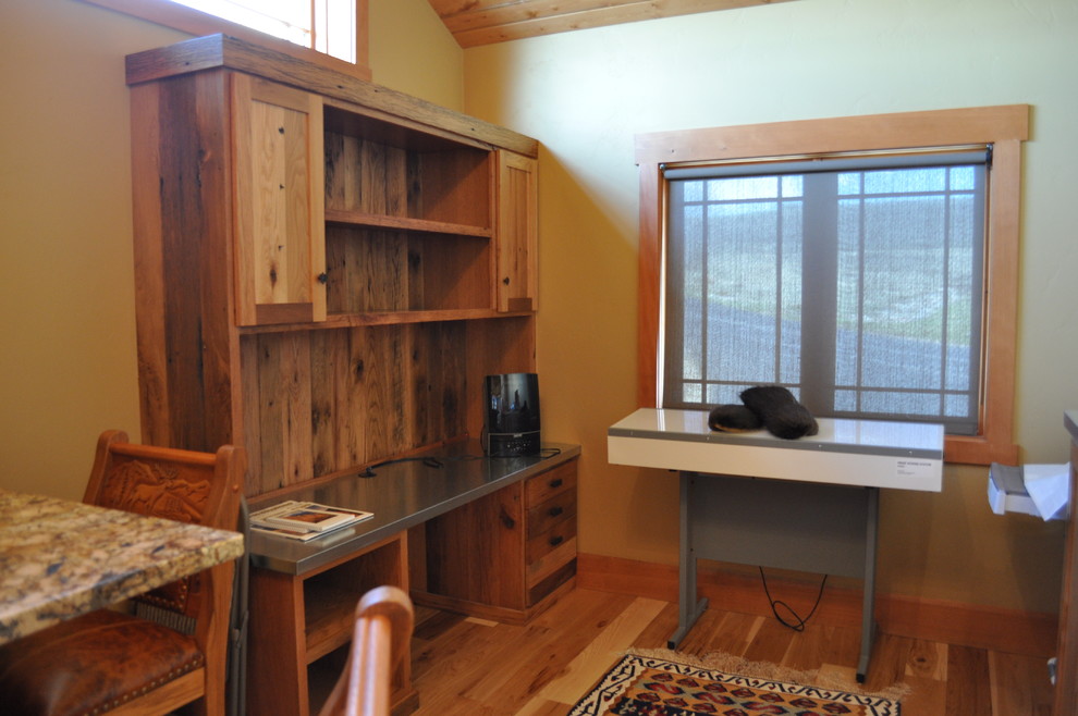 This is an example of a large rustic home office in Orange County with beige walls, light hardwood flooring and a built-in desk.