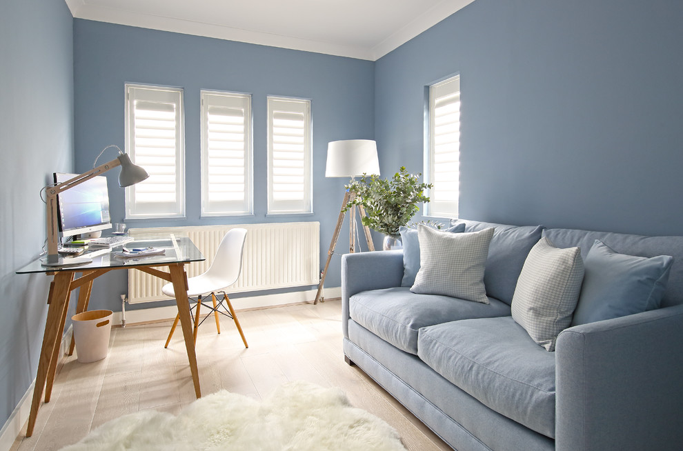 Imagen de estudio clásico renovado con paredes azules, suelo de madera clara y escritorio independiente