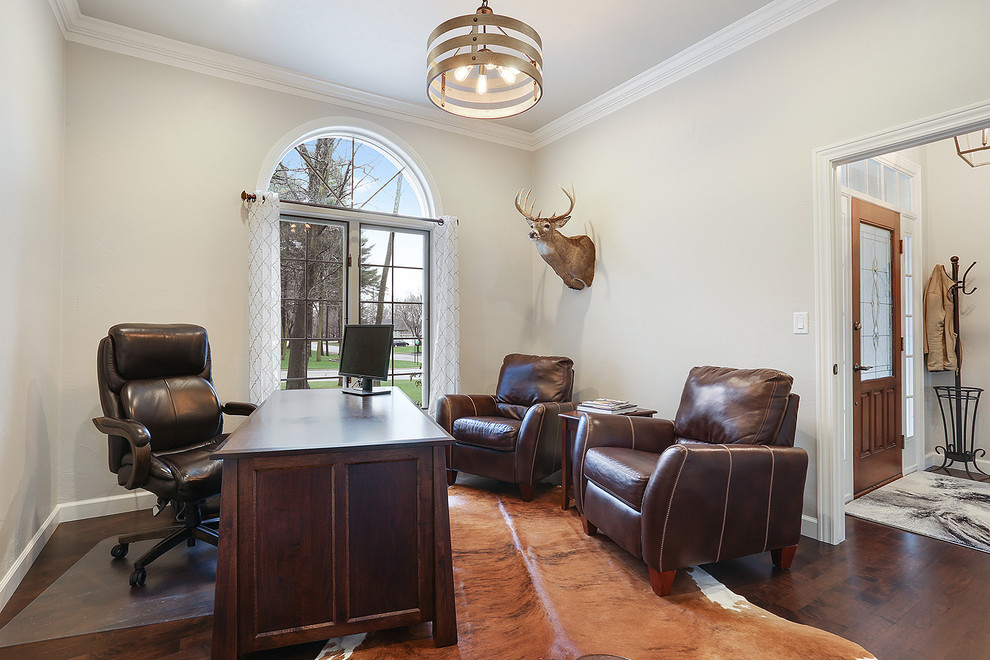 Klassisches Arbeitszimmer mit grauer Wandfarbe, braunem Holzboden, freistehendem Schreibtisch und braunem Boden in Sonstige