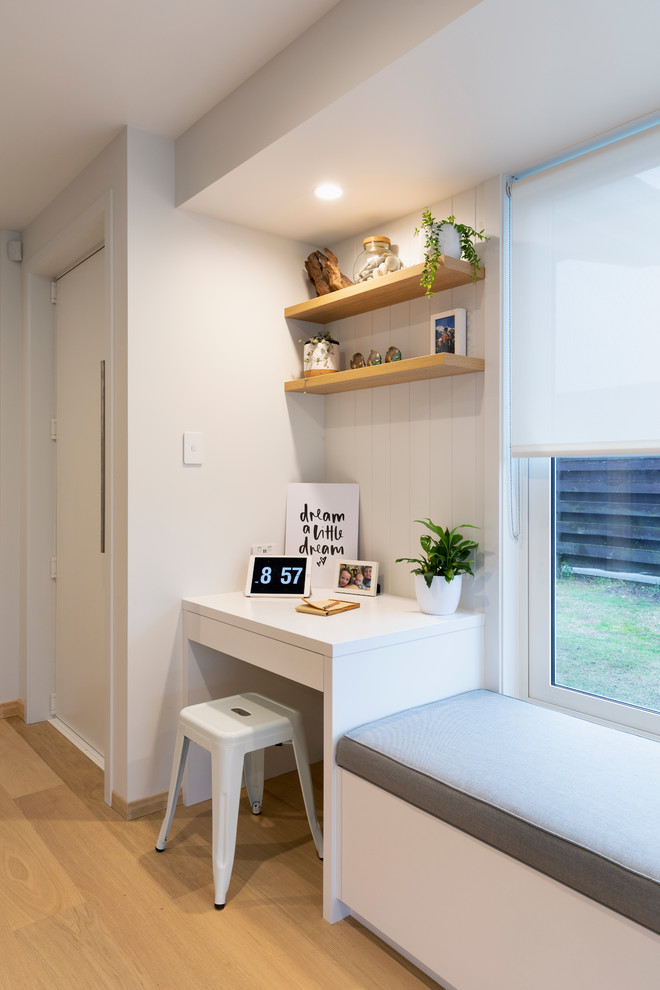 Kleines Modernes Arbeitszimmer mit Arbeitsplatz, weißer Wandfarbe, braunem Holzboden und Einbau-Schreibtisch in Sonstige