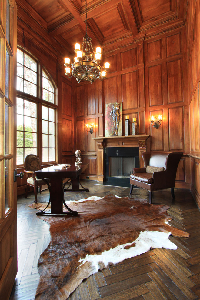 Exempel på ett klassiskt arbetsrum, med mörkt trägolv, en standard öppen spis och ett fristående skrivbord