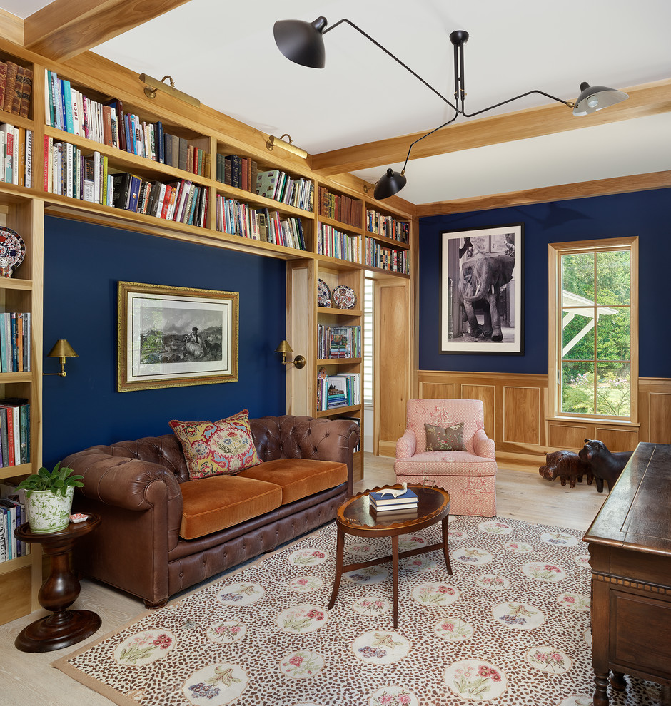 Ejemplo de despacho clásico con biblioteca, paredes azules, suelo de madera clara, escritorio independiente y suelo beige