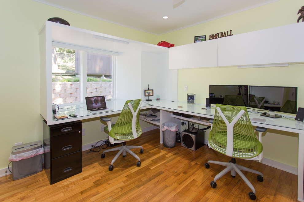 Exempel på ett modernt arbetsrum, med gröna väggar, mellanmörkt trägolv och ett inbyggt skrivbord