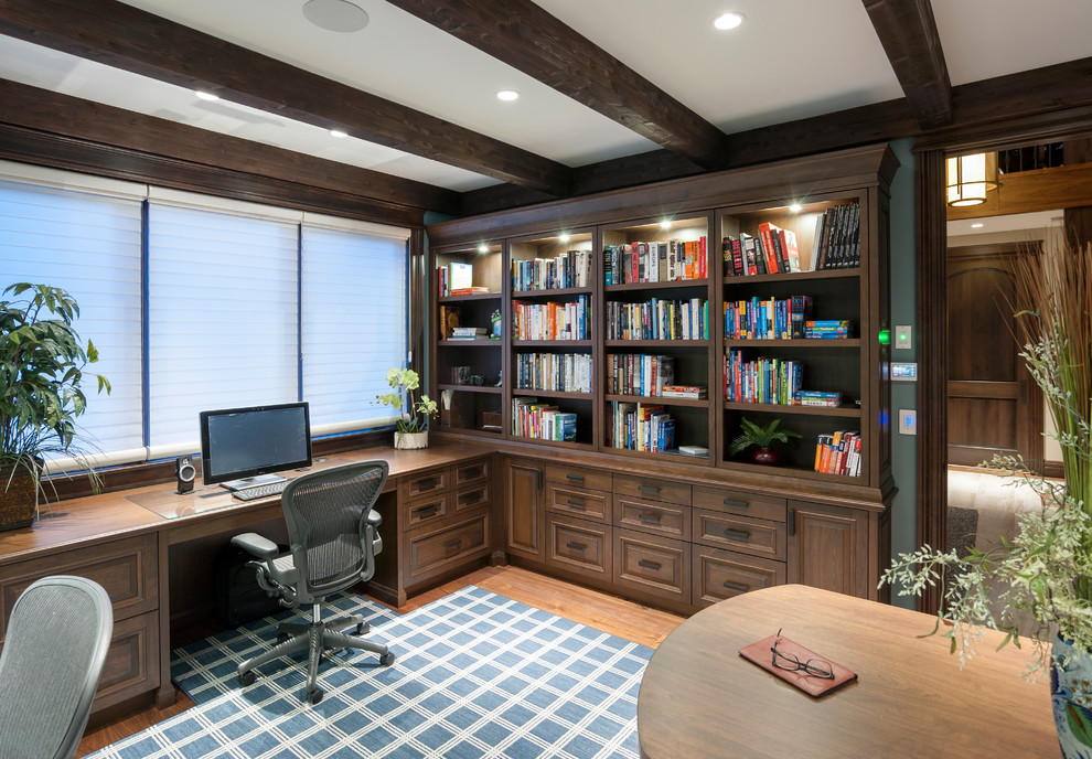 This is an example of a rustic study in Calgary with blue walls, medium hardwood flooring, a built-in desk and brown floors.