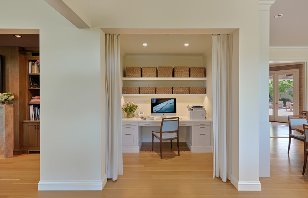 Modelo de despacho clásico renovado pequeño sin chimenea con paredes beige, suelo de madera clara, escritorio empotrado y suelo beige