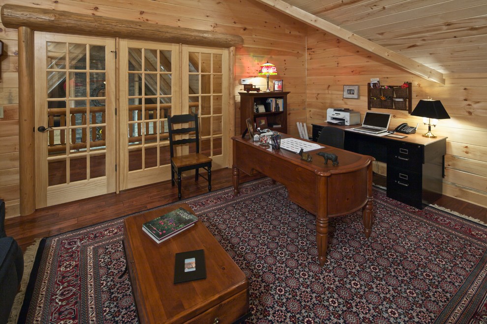 Inspiration för ett rustikt hemmabibliotek, med mörkt trägolv och ett fristående skrivbord
