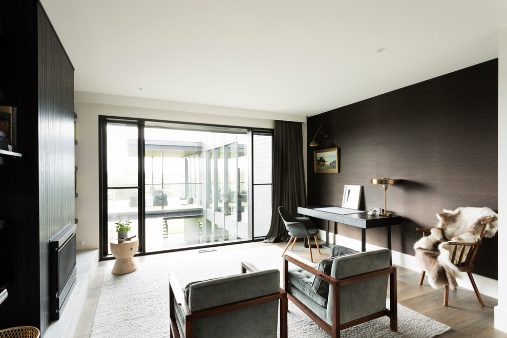 Example of a large danish freestanding desk medium tone wood floor study room design in Melbourne with white walls, a standard fireplace and a wood fireplace surround