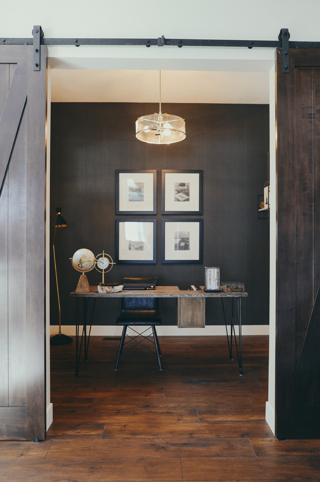 Example of a large mountain style freestanding desk dark wood floor and brown floor study room design in Calgary with black walls