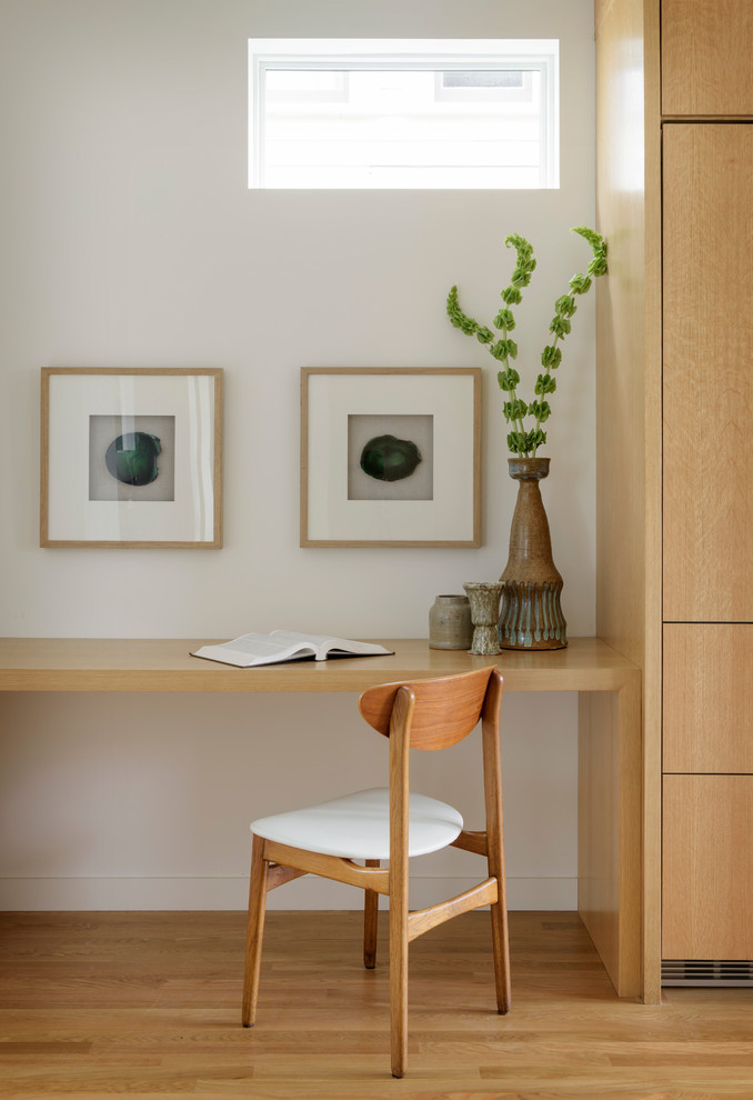 Esempio di uno studio minimal con pareti bianche, pavimento in legno massello medio, scrivania incassata e pavimento marrone