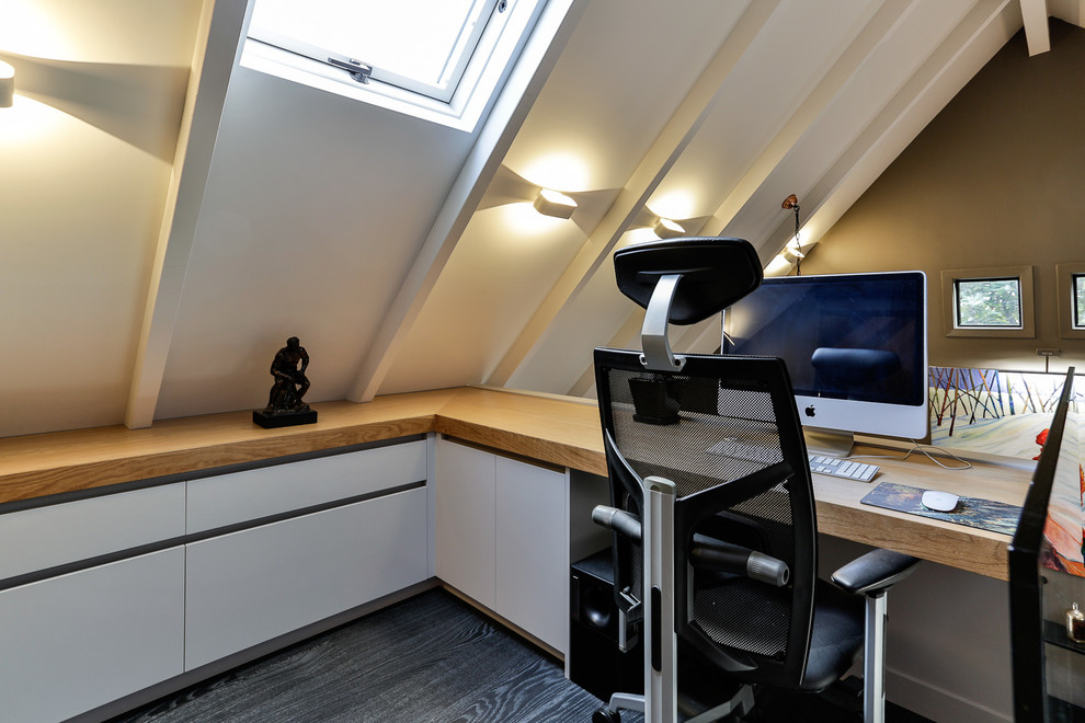 Example of a small urban built-in desk dark wood floor study room design in Auckland with white walls