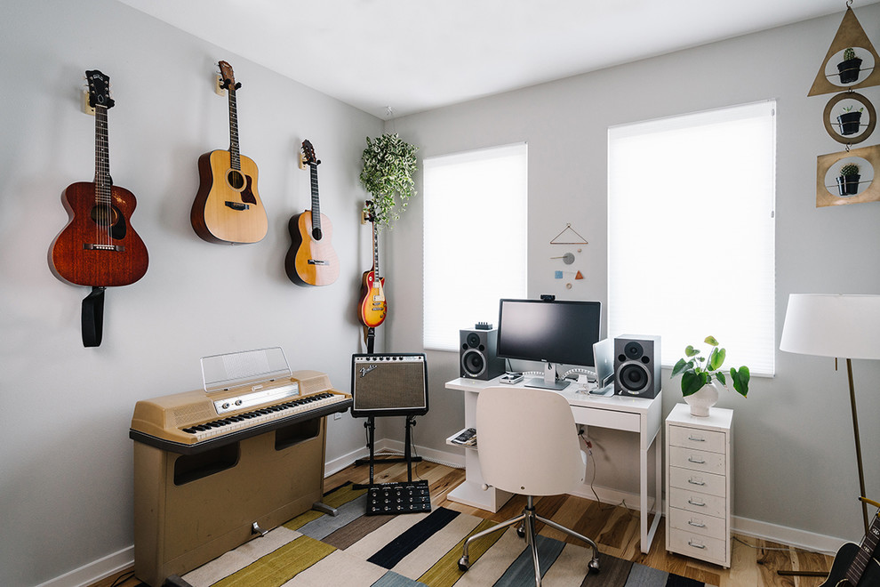 Cette image montre un bureau nordique de taille moyenne et de type studio avec un mur gris, un sol en bois brun, aucune cheminée et un bureau indépendant.
