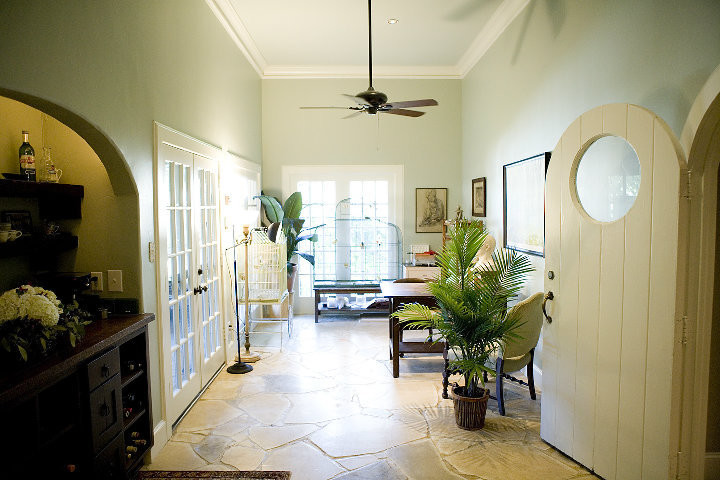 Imagen de despacho bohemio de tamaño medio con paredes verdes, suelo de piedra caliza, escritorio independiente y suelo beige