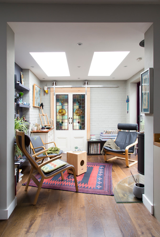 Cette image montre un bureau bohème de type studio avec un mur gris et un sol en bois brun.