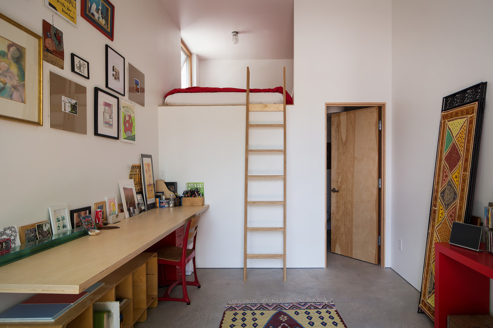 Immagine di un atelier minimal con pareti bianche, pavimento in cemento e scrivania incassata