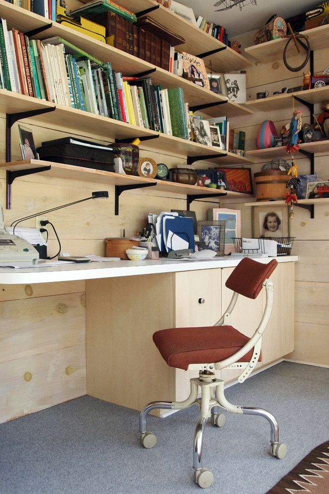Photo of a midcentury home office in New Orleans with a built-in desk and grey floors.