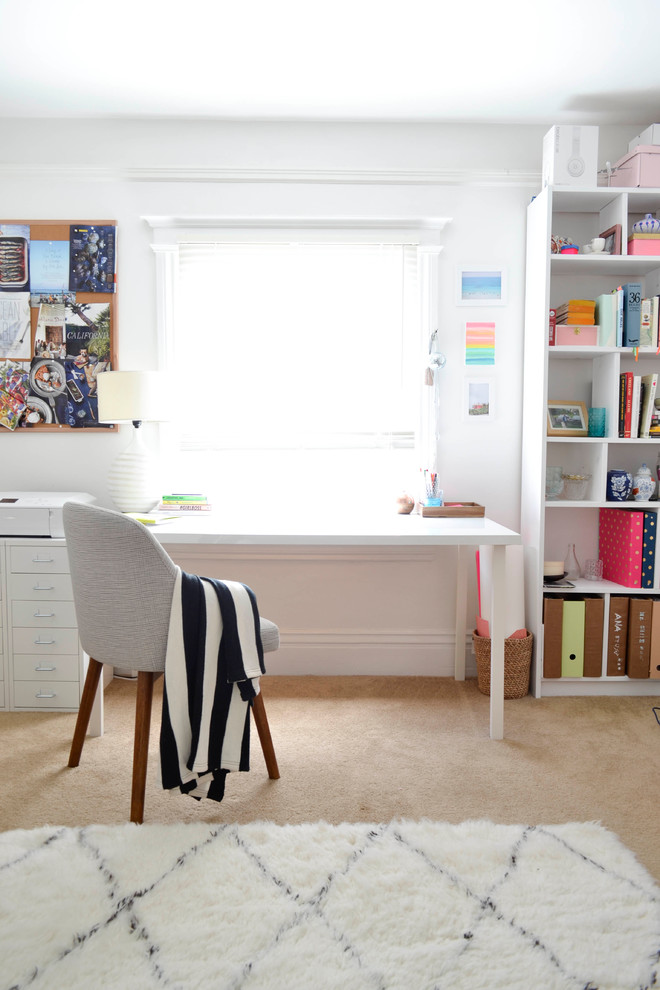Exempel på ett litet eklektiskt hemmabibliotek, med vita väggar, heltäckningsmatta och ett fristående skrivbord