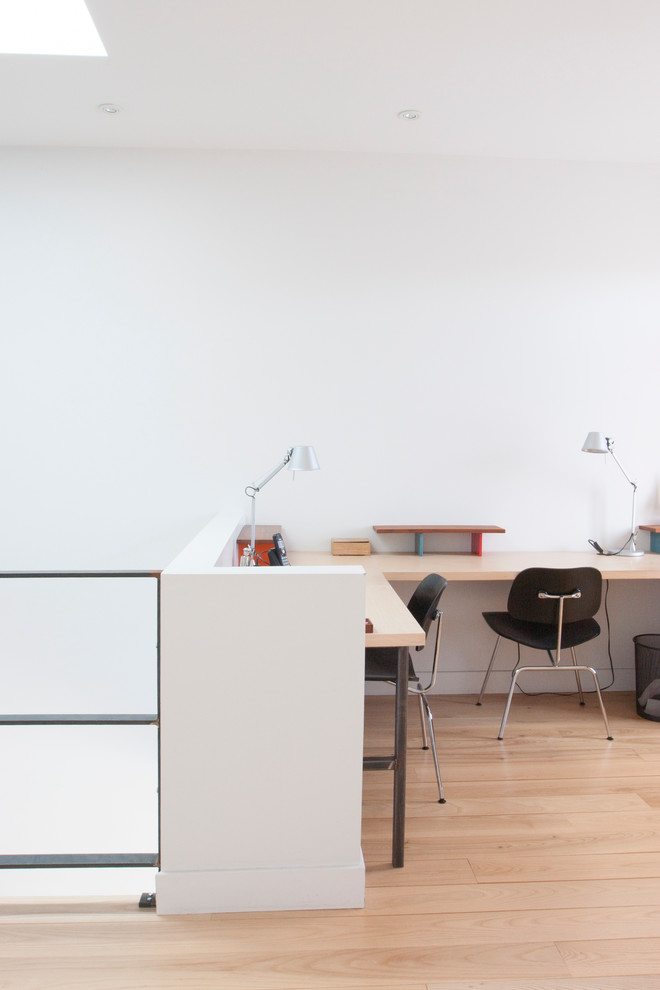 Bild på ett funkis arbetsrum, med vita väggar, ljust trägolv och ett inbyggt skrivbord
