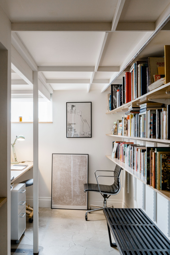 Idéer för att renovera ett litet industriellt hemmabibliotek, med vita väggar, betonggolv, ett inbyggt skrivbord och grått golv