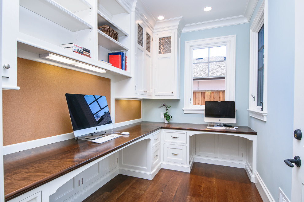 Foto de despacho clásico con paredes azules, suelo de madera en tonos medios y escritorio empotrado