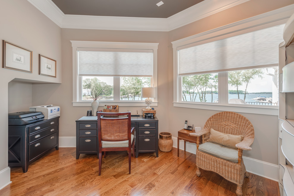 Mid-sized beach style freestanding desk medium tone wood floor and brown floor study room photo in Charlotte with beige walls and no fireplace