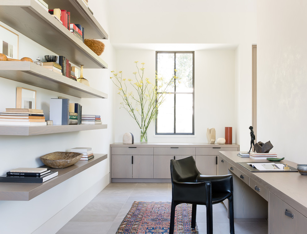 Photo of a rural home office in San Francisco with white walls, a built-in desk and grey floors.
