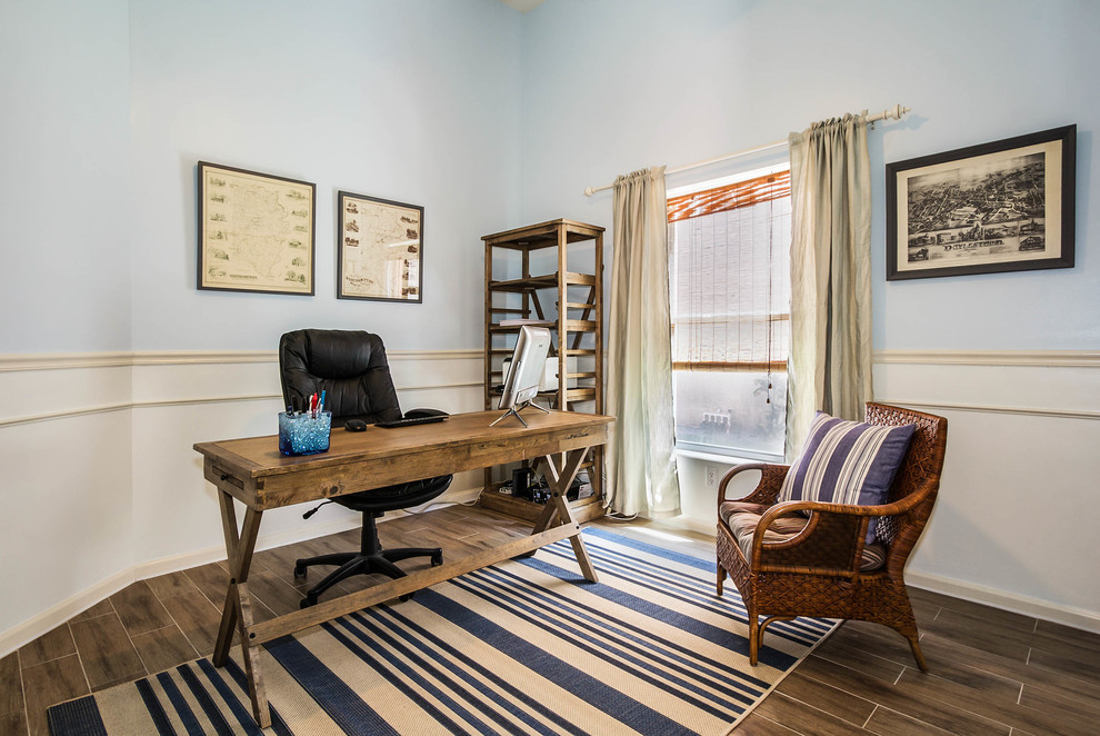 Maritimes Arbeitszimmer mit Arbeitsplatz, blauer Wandfarbe, braunem Holzboden und freistehendem Schreibtisch in Miami
